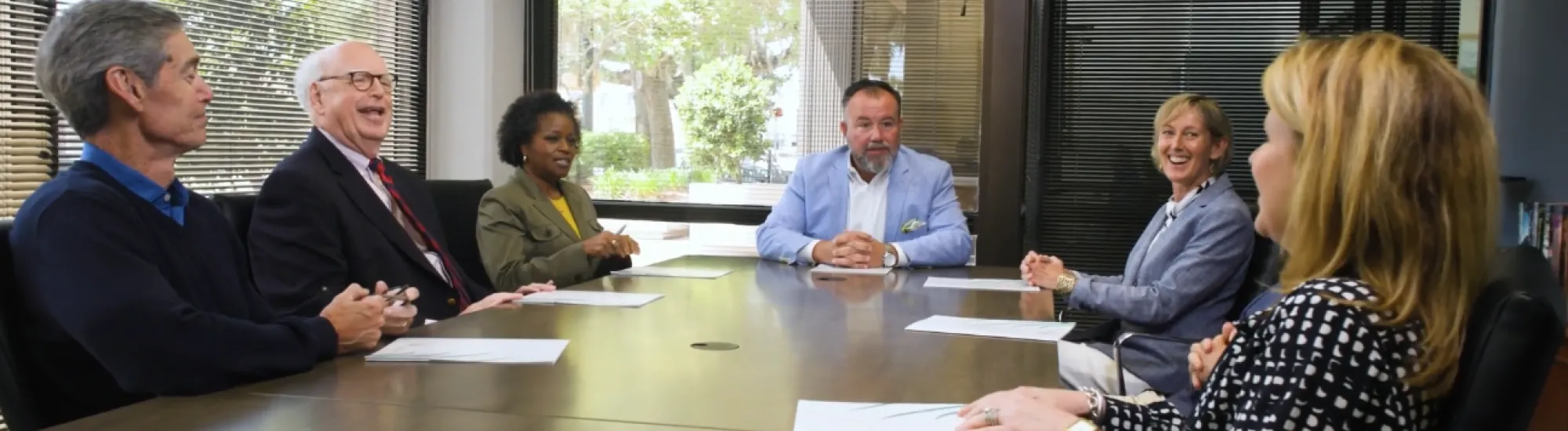 A group of six people having a meeting around a conference table.
